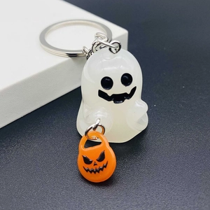 Macro shot of luminous ghost keychain with orange pumpkin basket for Halloween