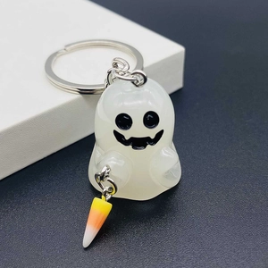 Close-up of luminous white resin ghost keychain with classic candy corn charm detail