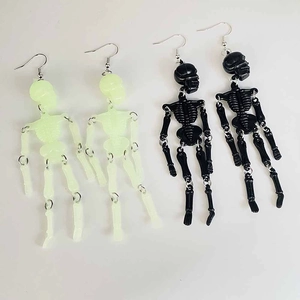 Detail view of articulated skeleton earrings in black and glow-in-the-dark neon green