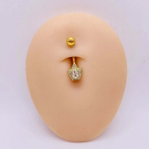 Détail d'un piercing de nombril couronne dorée avec zircons sur modèle peau
