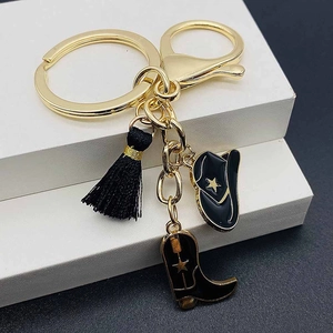 Detail of western cowboy keychain with black enamel hat, boot charm and fringe tassel