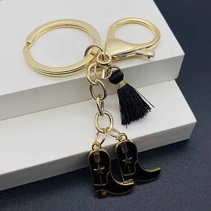 Detail of pink western cowboy keychain with black tassel and star-etched boots pendants
