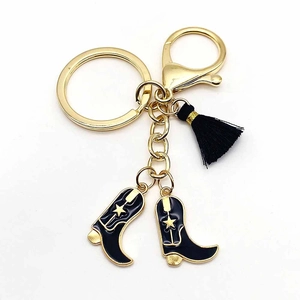 Western cowboy keychain featuring black enamel boots with gold stars and silk fringe tassel