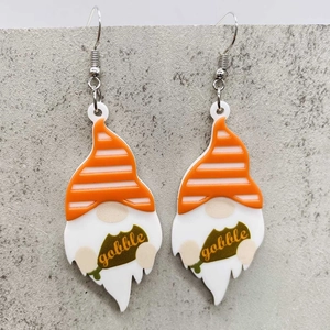 Nahaufnahme von Thanksgiving-Zwergohrringen aus Acryl mit Gobble-Text auf grauem Grund