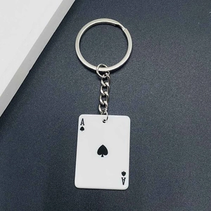 Detail of Ace of Spades poker pendant keychain with silver metal ring on textured background