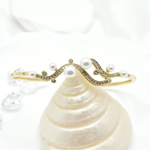 Detail of 18k gold plated wave bangle featuring white pearls and micro-pave cubic zirconia