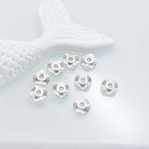Macro shot of silver heart spacer beads with radial texture for DIY jewelry making