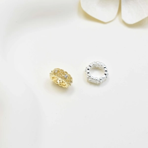Intricate hollow-out spacer charms in gold and silver with cubic zirconia inlays