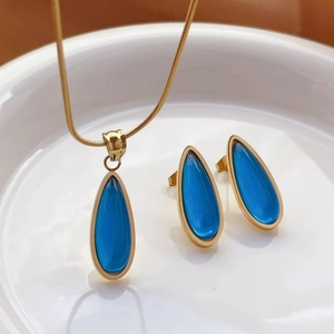 Water drop jewelry set with blue pendant necklace and earrings on white ceramic