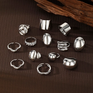 Set of minimalist silver geometric rings with irregular lava textures on dark leather