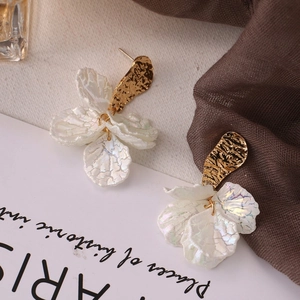 Detailed macro view of pearlescent white flower petals and golden hammered metal earrings