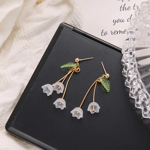 Detail showing elegant lily of the valley earrings with white petals and green leaves