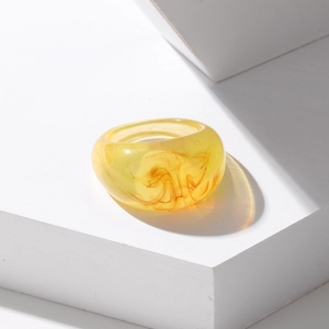 Macro detail of yellow translucent resin ring with amber texture on a white pedestal