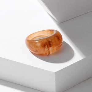 Detailed macro view of amber resin ring with marble texture on minimalist white platform