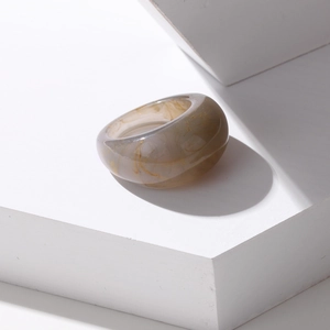 Macro view of a thick translucent resin ring with amber foil textures on a minimalist base