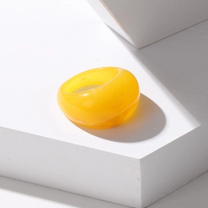 Macro detail of a smooth yellow resin ring showcasing translucent texture and minimalist style