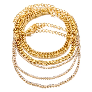 Dettaglio di catene cubane dorate a strati e cavigliere tennis con strass brillanti