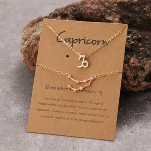 Makro-Detail der goldenen Steinbock-Halskette mit Strass-Armband auf brauner Karte