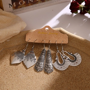 Drei Paar silberne Boho-Ohrringe im Vintage-Stil auf Karte mit feinen Blumenmustern