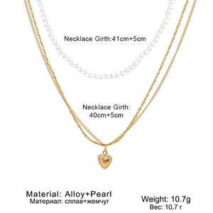 Détail du collier multicouche en alliage doré avec perles blanches et pendentif cœur