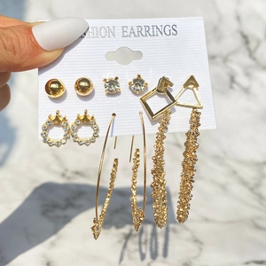 Dettaglio di 6 paia di orecchini vintage dorati con strass su un supporto di carta bianca