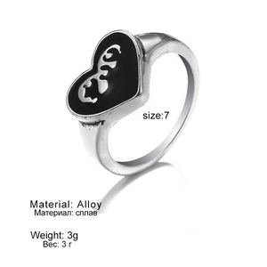 Macro view of vintage heart-shaped alloy ring featuring black enamel and silver textures