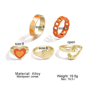 Detailansicht eines fünfteiligen Goldlegierungsringsets mit orangefarbenen Herzdetails