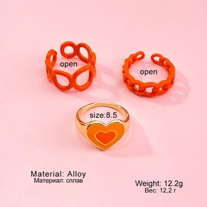 Nahaufnahme von drei orange-goldenen Ringen mit Herz- und Kettendesign und Öl-Finish