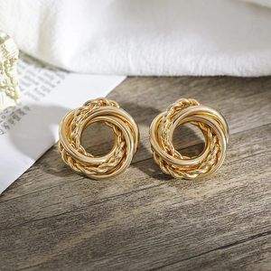 Makroaufnahme goldener Creolen mit Seilstruktur und glatten Ringen auf dunklem Holz