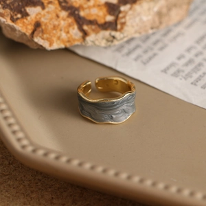 Detalle de un anillo esmaltado con textura de mármol gris sobre un plato decorativo