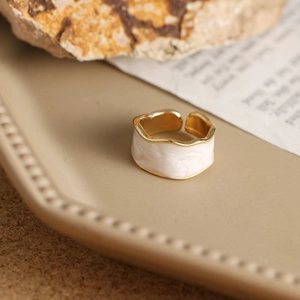 Vista de detalle de anillo dorado ondulado con incrustación de mármol en bandeja