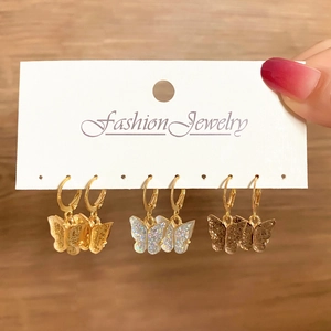 Close-up of three pairs of glitter butterfly drop earrings on a fashion display card