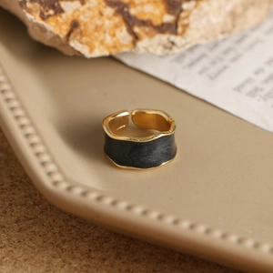 Detalle de cerca de un anillo ondulado dorado vintage con acabado de esmalte negro