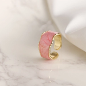 Anillo abierto de esmalte rosa con borde ondulado y textura de mármol dorado
