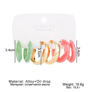 Detailed view of large C-shaped acetate earring set in mint green, gold, and coral pink