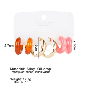 Detailed view of three pairs of C-shaped resin and gold alloy earrings on display card