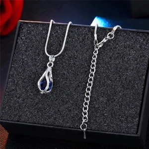 Détail du collier chaîne serpent argentée avec pendentif larme creuse et cristal bleu