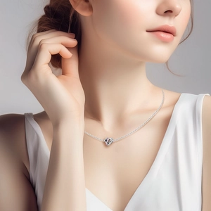Silver heart pendant necklace with pink stones and Love engraving on a female model