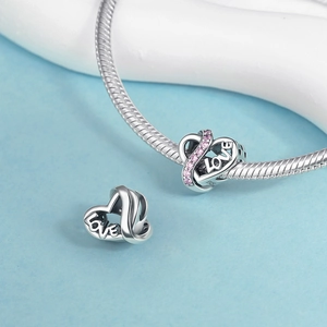 Makroaufnahme vom silbernen Herzanhänger mit rosa Kristallen und LOVE-Gravur am Armband