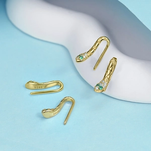 Detailweergave van vergulde slangenoorringen in 925 zilver met groene edelstenen