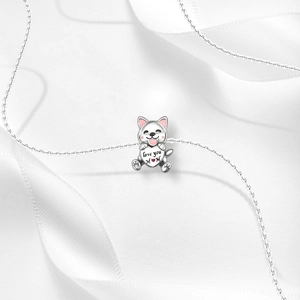 Close-up of silver puppy pendant with Love you MOM heart on soft white silk ribbon