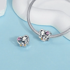 Detail of silver heart charm with pink stone and fox relief on snake chain bracelet