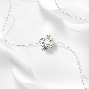 Detailed macro of silver elephant pendant with pink heart gemstone and gold crown