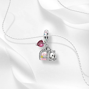Macro shot of S925 sterling silver pet charm with pink enamel pet bag and heart gemstone