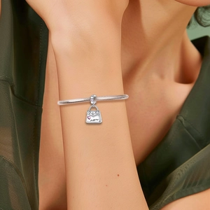 Silver snake chain bracelet featuring a shopping bag charm with pink hearts and cubic zirconia