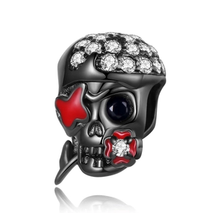 Macro shot of silver-plated skull charm with white zircons and red enamel flower detail