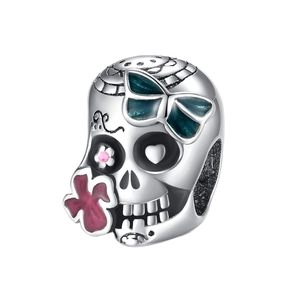 Detail of silver skull charm with turquoise bow and floral enamel patterns