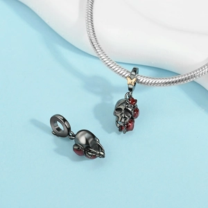 Macro shot of skull pendants with black plating, red roses and gold butterfly accents