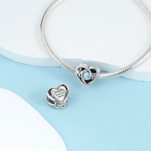 Macro shot of silver heart charm with blue stone and Always knows best engraving