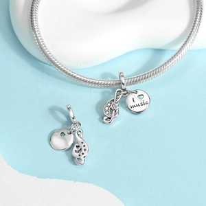 Detalle de colgante musical de plata con gema de corazón rosa y grabado I Love Music